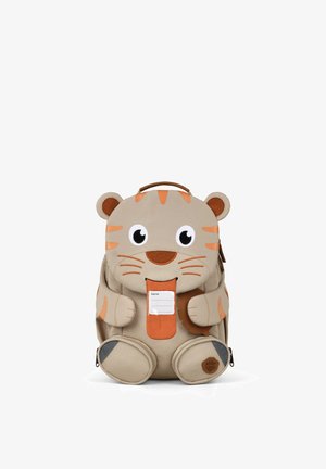Children's backpack shaped like a beige and orange tiger with big eyes, ears, paws, and a visible name tag on the front.