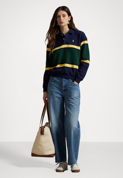 Navy and green striped polo shirt with yellow accents, paired with light blue wide-leg jeans and a cream bag with brown handles.