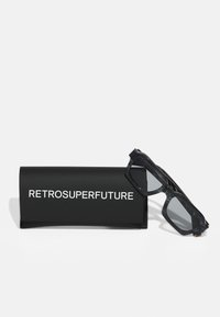 Schwarze Sonnenbrille mit grauen Gläsern, ausgestattet mit einem massiven Rahmen im marmorierten Muster. Begleitet von einem schwarzen Etui mit der Aufschrift "RETROSUPERFUTURE".