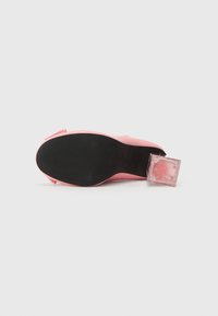 Roze hoge hak schoen met een slank ontwerp, glanzend materiaal en een doorschijnende, vierkante hak. De zool is zwart met gestructureerde groeven.