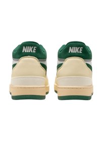 Nike lenkkarit, joissa on vihreä mokkanahka ja kerma valkoinen nahkainen päällinen, vaalean beige välikerros ja vihreä ulkopohja. Valkoinen Nike-logo kantapäässä.