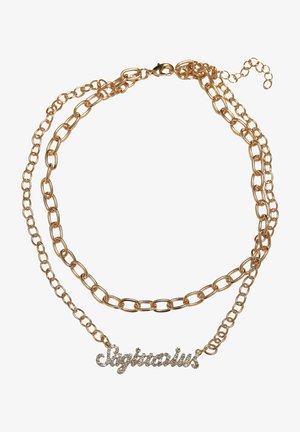 Guldtonet lagdelt kæde halskæde med en kursiv "Skytten" vedhæng prydet med klare rhinsten. Kæderne varierer i ledstørrelse.