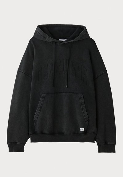 Fekete pamut kapucnis sweatshirt, nagy elülső zsebbel, húzózsinórral ellátott kapucnival és dombornyomott logóval. A passzos illeszkedés érdekében bordázott mandzsettákkal és alsó résszel rendelkezik.