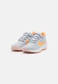 Baskets de sport gris clair avec des accents orange, tige texturée, lacets avec œillets intégrés et une semelle blanche matelassée.