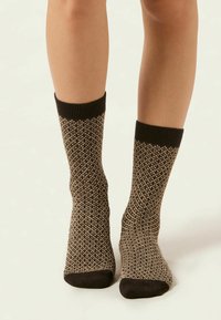 Kniestrümpfe mit einem strukturierten Strickmuster in Schwarz und Braun, mit einem einfarbigen, schwarzen gerippten Bündchen und einer dunklen Zehenpartie.