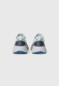 Scarpe da ginnastica azzurro chiaro con una parte superiore testurizzata, dettagli grigi e una suola in gomma con un motivo di battistrada blu. Vista posteriore.