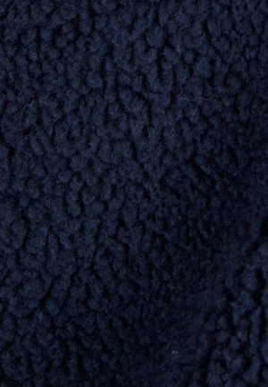 Marineblauwe fleece stof met een gestructureerd, zacht oppervlak en een verhoogd patroon. De stof lijkt weelderig en pluizig.