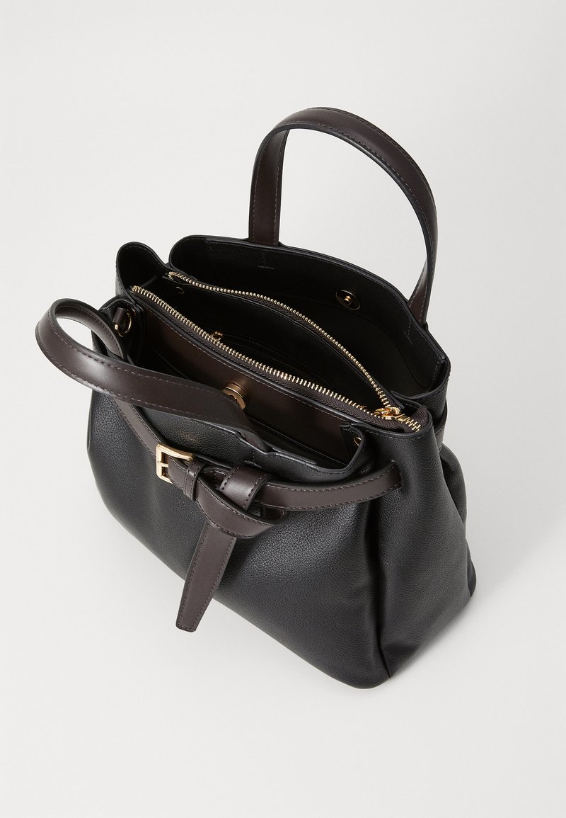 Sac à main en cuir noir avec une forme structurée, deux poignées, une bandoulière ajustable et un détail de fermeture éclair doré, révélant des compartiments intérieurs.