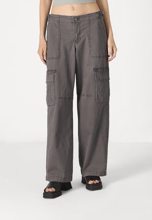 Grey cargo pants made of breathable fabric, featuring large side pockets, loose fit, and stitched details along the seams.