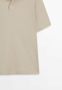 Beige polo shirt made from textured fabric, featuring a collared neckline and two button placket, with short sleeves and a standard fit.