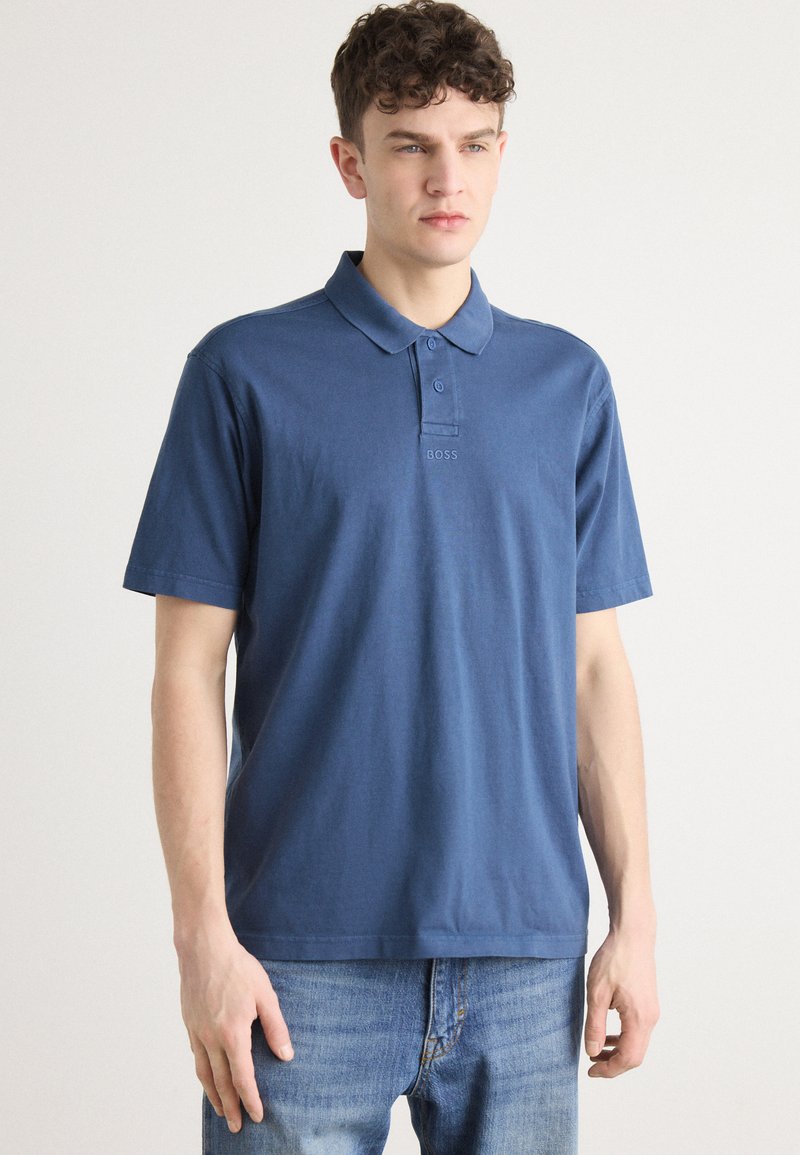 Μπλέ πόλο μπλούζα από βαμβάκι, με τρεις κουμπάκια, κοντά μανίκια και μικρό λογότυπο κεντημένο στο στήθος.