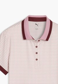 Kurzärmliges Poloshirt in Weiß mit einem roten geometrischen Muster. Verfügt über einen burgunderfarbenen Kragen und fünf braune Knöpfe an der Knopfleiste.