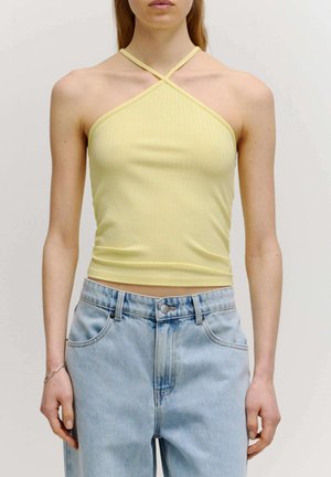 Gelbes, geripptes Trägershirt mit einem Kreuzdesign der Träger, das eine taillierte Silhouette und eine glatte Textur aufweist, kombiniert mit hellblauen Jeans.