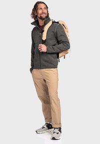 Grau zip-up Fleece-Jacke mit strukturiertem Stoff, beiger Hose und Turnschuhen. Rucksack in hellem Beige mit verstellbaren Trägern.