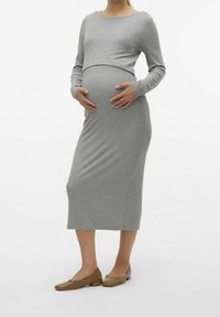 Grå gravidklänning med långa ärmar, figursydd form och mjuk textur. Matchad med ljusbruna platta skor, vilket skapar en enkel och sammanhängande look.