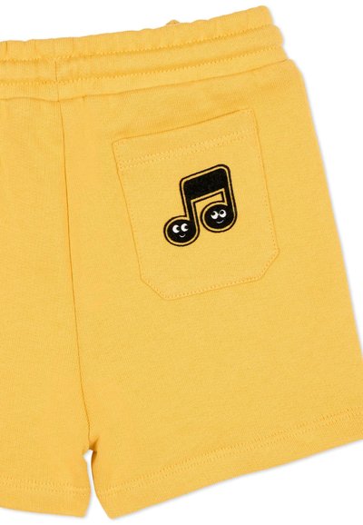 Shorts jaunes pour tout-petit avec taille élastique et poche arrière ornée d'une note de musique noire avec des yeux souriants.