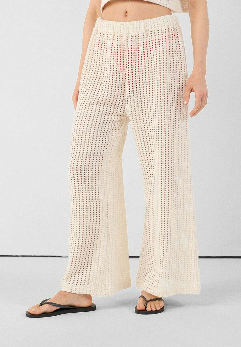 Wijdvallende broek van textuurrijke crème stof met een geruit patroon, voorzien van een elastische tailleband en een relaxte pasvorm.