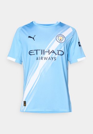 Camiseta de fútbol de manga corta en azul claro con una franja diagonal blanca, logo negro de Puma, "ETIHAD AIRWAYS" impreso en azul oscuro y el escudo del club.
