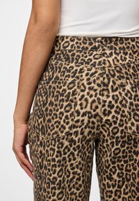 Jeans cu imprimeu leopard dintr-un amestec de bumbac, cu buzunare pe spate, talie medie și un design ajustat cu un material texturat.