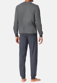 Sweatshirt à manches longues gris à motif, avec des poignets côtes, associé à un jogging gris ample avec des chevilles élastiques.