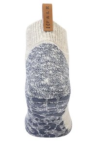 Zapatilla de punto con una base crema y acentos de patrón en azul marino. Presenta una etiqueta de imitación de cuero marrón en la parte trasera y una suela texturizada.