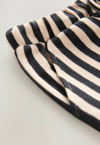 Primo piano di tessuto morbido con strisce orizzontali nere e beige e cuciture visibili su uno sfondo chiaro.