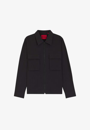 Veste noire zippée avec col pointu et deux poches avant à rabat, avec une étiquette rouge Hugo à l'intérieur du col.