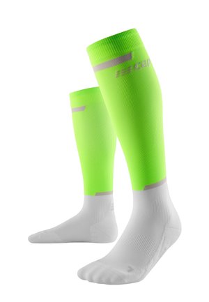 Calze compressive verde neon con base bianca, dotate di texture a coste e strisce grigie riflettenti vicino alla parte superiore per una maggiore visibilità.