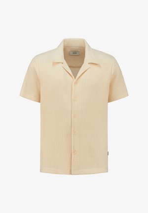 Camisa de manga corta de color beige claro, hecha de un tejido texturizado de punto en waffle, con cuello y cinco botones de cierre.