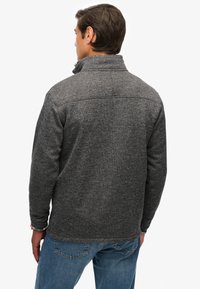 Grijze fleece trui met een hoge kraag en lange mouwen, voorzien van een gestructureerd patroon en een rechte zoom. Achteraanzicht toont een casual pasvorm.