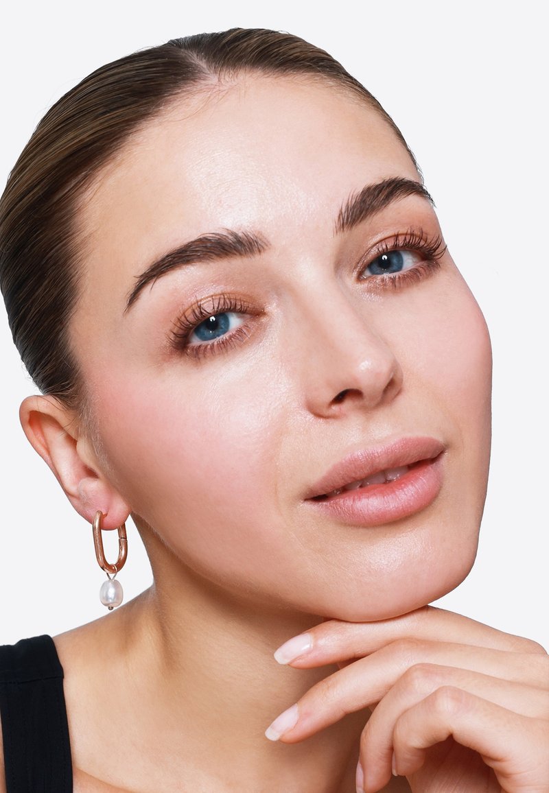 Goldene Creolen mit einem Perlenakzent, die eine glatte, glänzende Oberfläche aufweisen. Das Design ist modern und zeigt eine minimalistische Ästhetik.