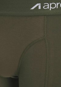 Olivgrüne Boxershorts aus glattem Stoff, mit einem breiten Bund, auf dem der Markenname "apron" in weißen Buchstaben steht.