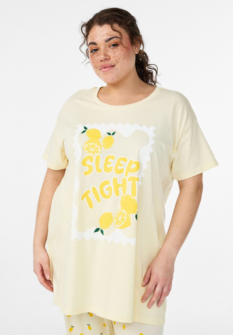 Gaiši dzeltena extra lieluma T-krekls no mīkstas auduma, ar citronu grafisko dizainu un uzrakstu "SLEEP TIGHT" treknās dzeltenās burtiņās.