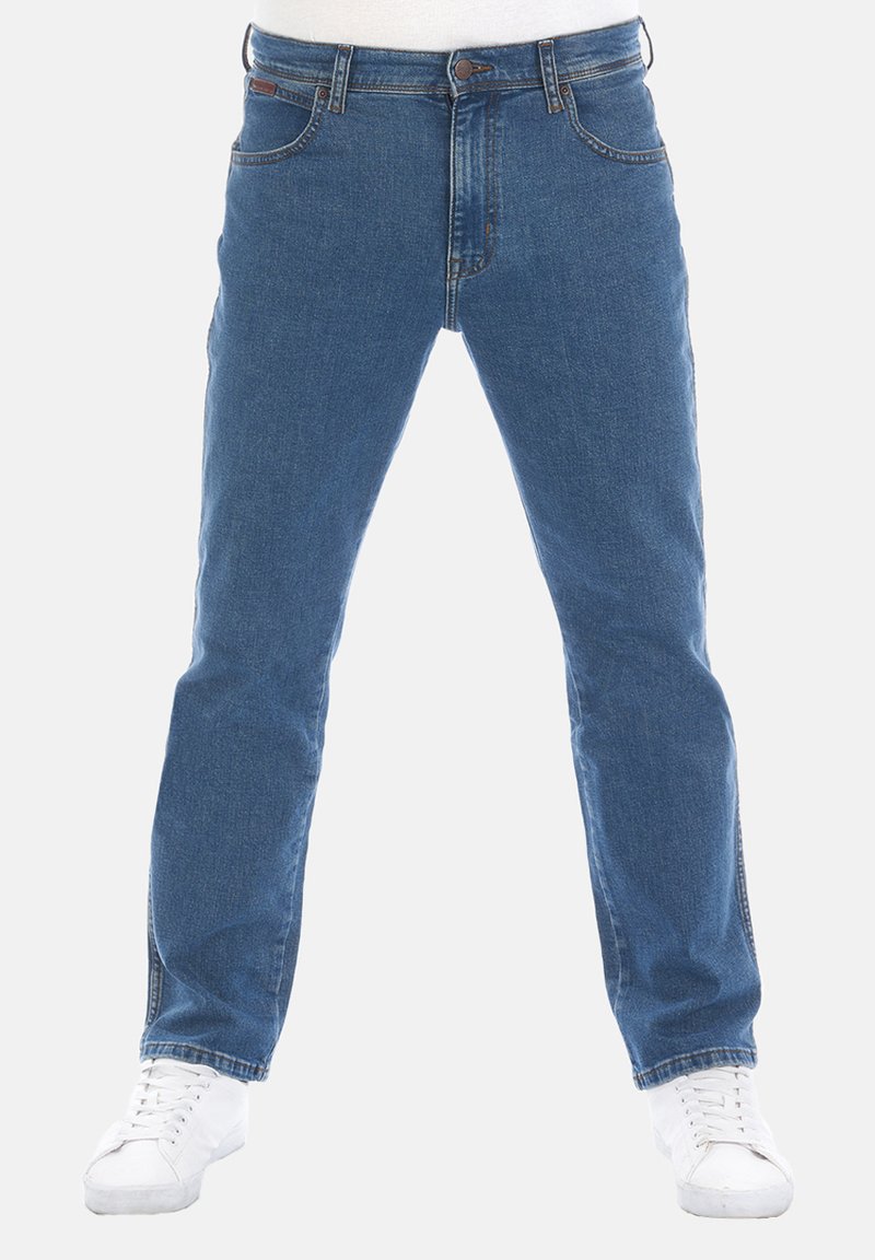 Jeans in denim blu con vestibilità dritta, cinque tasche, chiusura con bottone in metallo e cuciture chiare. Abbinati a sneakers bianche.