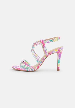 Sandale à talon haut avec brides florales colorées, bout ouvert, fermeture à boucle et talon aiguille sur fond clair.