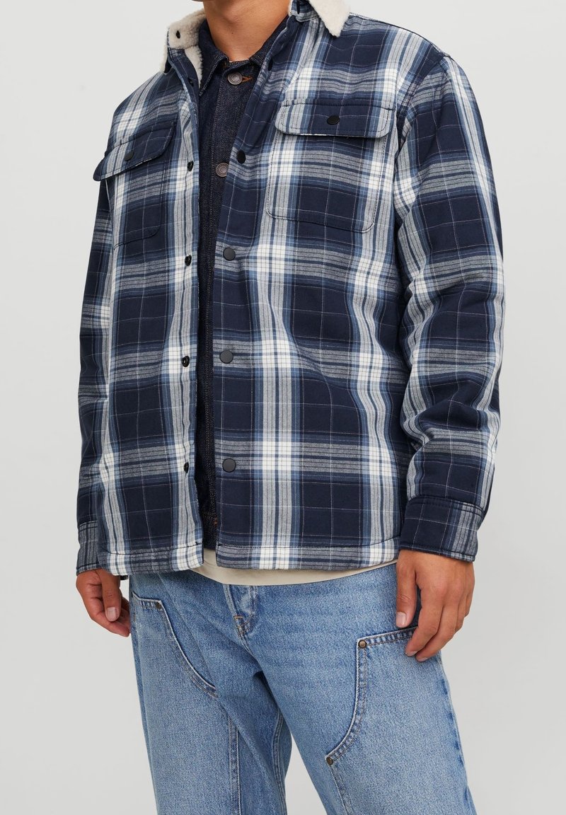 Marineblå och vit rutigt skjortjacka med knäppning, två framfickor och en beige fleecekrage; blandat bomullstyg, avslappnad passform.