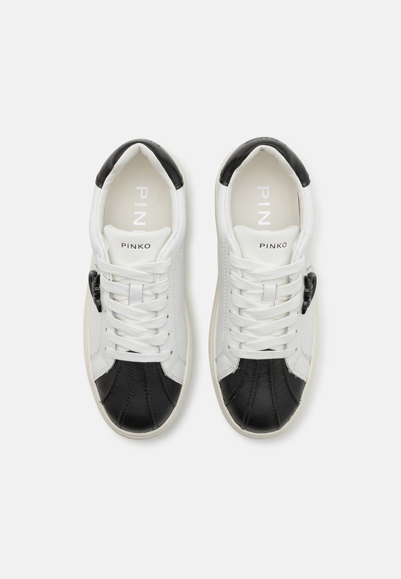 Weiße und schwarze Leder-Sneaker mit glatter Oberfläche, ausgestattet mit einer weißen Schnürung, einem Logo auf der Zunge und kontrastierenden, strukturierten Elementen.