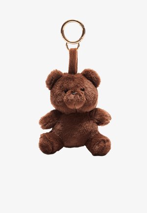Smeđi plišasti privjesak u obliku medvjedića s okruglim ušima, malim udovima i izvezenim facialnim značajkama, s zlatnim metalnim prstenom i svijetlosmeđom trakom.