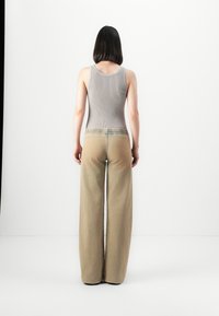 Ribbed gray tank top with wide-leg beige trousers. The pants feature a gathered waistband and light, smooth texture.