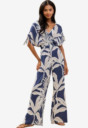 Navy blue jumpsuit with wide leg and batwing sleeves, featuring a white botanical print. Smooth texture with a cinched waist detail.