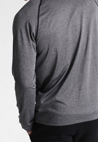 Graues Langarmshirt aus weichem, dehnbarem Stoff, mit glatter Textur und lockerer Passform, minimalen Nähdetails.