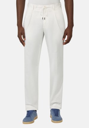 Pantalones ligeros blancos con una cinturilla ajustable y bolsillos laterales, con una textura suave, combinados con zapatos deportivos de ante azul.