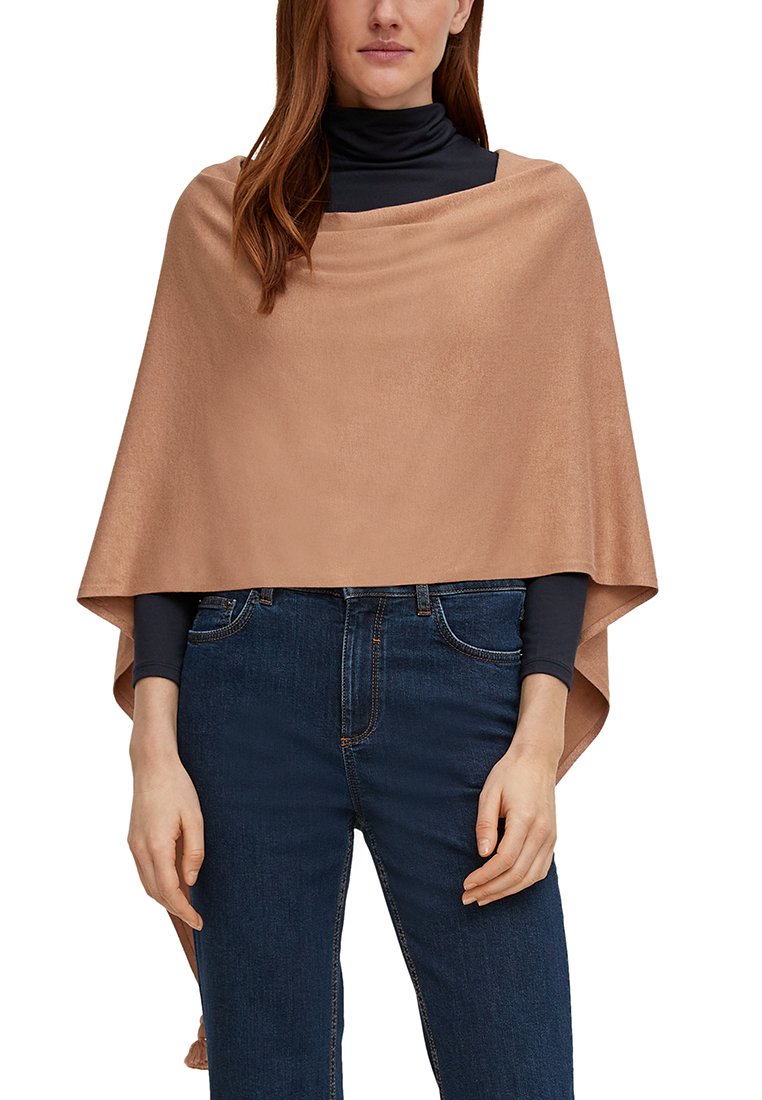Hellbeige Poncho aus weichem Stoff, mit einem drapierten Design und offenen Seiten, getragen über einem schwarzen Rollkragenpullover und dunklen Jeans.