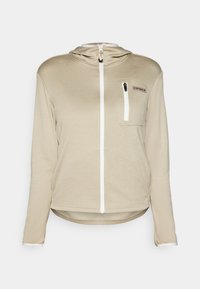Lys beige hettegenser med glidelås laget av strukturert stoff, med en frontlomme, hvit glidelås og en tettsittende hette. Har en lett bakover droppet hem.