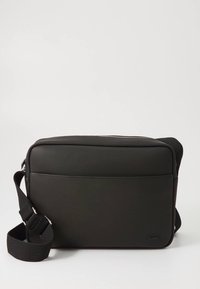 Schwarze synthetische Schultertasche mit texturierter Oberfläche, rechteckiger Form, verstellbarem Riemen, Reißverschluss oben und einer Vorderseite-Tasche.