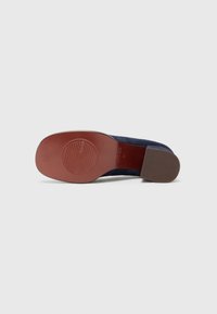 Navy blue suede shoe with a flexible brown rubber sole, featuring a textured pattern on the bottom and a slight heel.