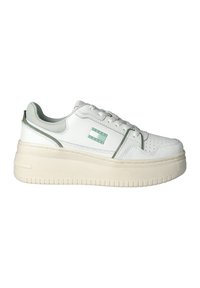 Sneaker bianca basse con suola spessa beige, rifiniture verdi, dettagli in mesh sul tallone e piccolo logo verde "Tommy Jeans" sul lato.