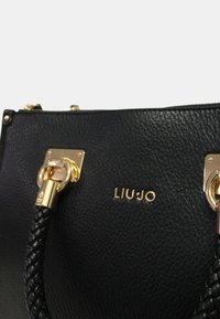 Borsa a tracolla in pelle nera con finitura testurizzata, hardware dorato, manico intrecciato e logo inciso "LIU JO" sul davanti.