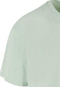 Miętowa koszulka z krótkim rękawem wykonana z miękkiej bawełny. Klasyczny krój z okrągłym dekoltem, prosty, gładki materiał i zaokrąglony dół.