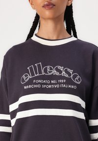 Sudadera de marina con textura acanalada y rayas blancas, con logo bordado en blanco. Cuello redondo con ribete blanco en contraste.